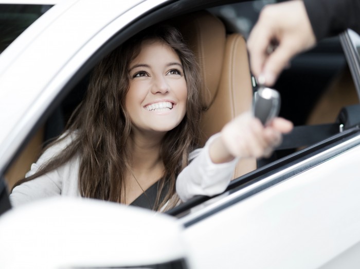 Young woman receiving the keys of her new car